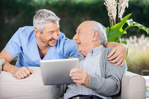 doctor with shoulders around an elderly man with a tablet