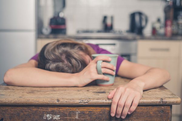 exhausted woman passed out with a cup of coffee on her hand
