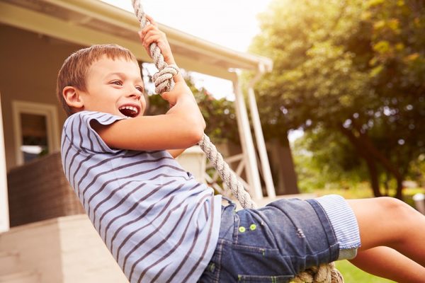 young boy smiling and swinging on a tire swing
