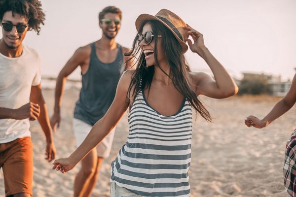 young woman smiling and having fun on the beach with two guys behind her