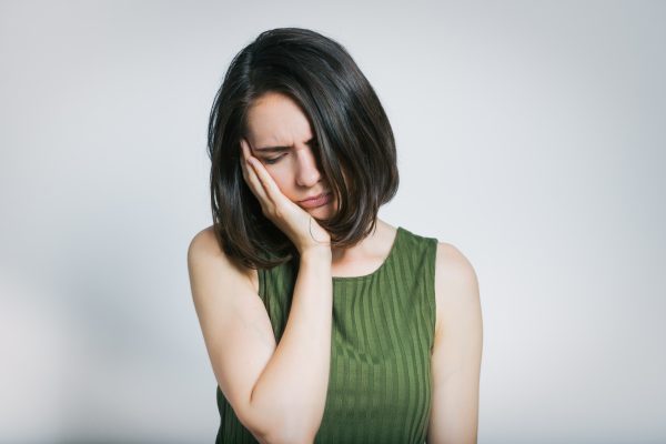 young woman holding her side of her face because of jaw pain
